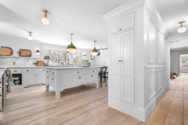 kitchen featuring a healthy amount of sunlight, light wood finished floors, ornamental molding, and light countertops