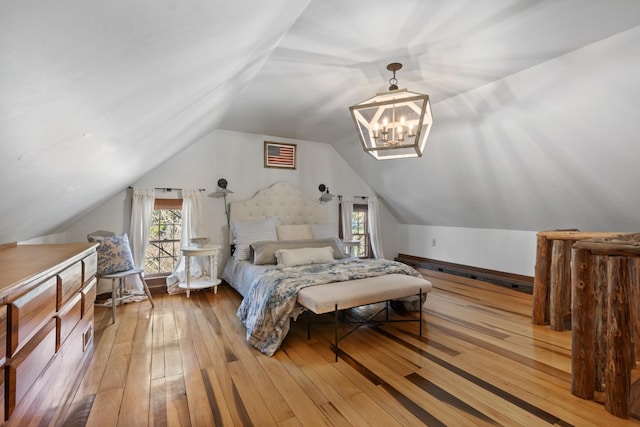 bedroom with vaulted ceiling, light wood-type flooring, visible vents, and an inviting chandelier