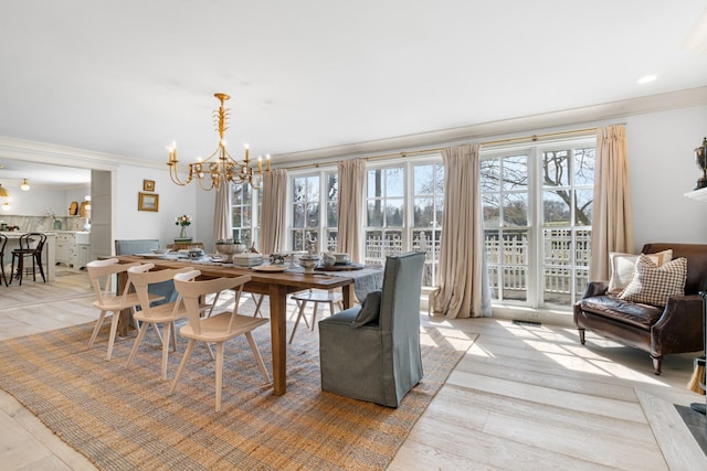 dining space with ornamental molding, a chandelier, and light wood-style flooring