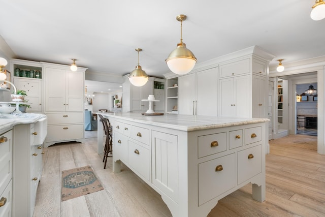 kitchen with white cabinets, light wood-style flooring, a kitchen island, and open shelves