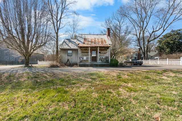 exterior space featuring metal roof, a chimney, fence, and a porch