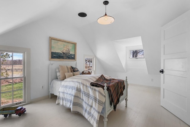 bedroom featuring lofted ceiling, multiple windows, baseboards, and wood finished floors