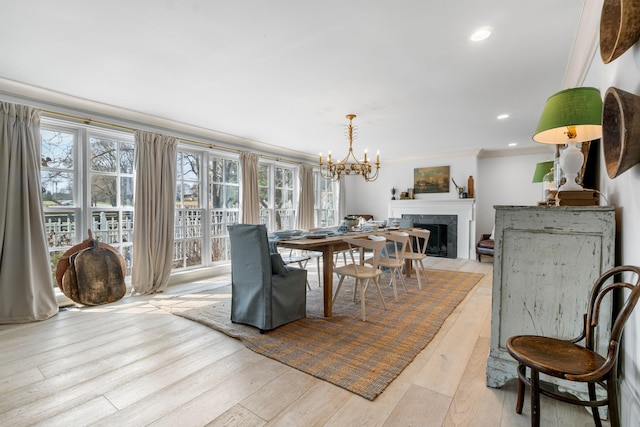 dining area with a fireplace with flush hearth, recessed lighting, crown molding, and light wood-style flooring