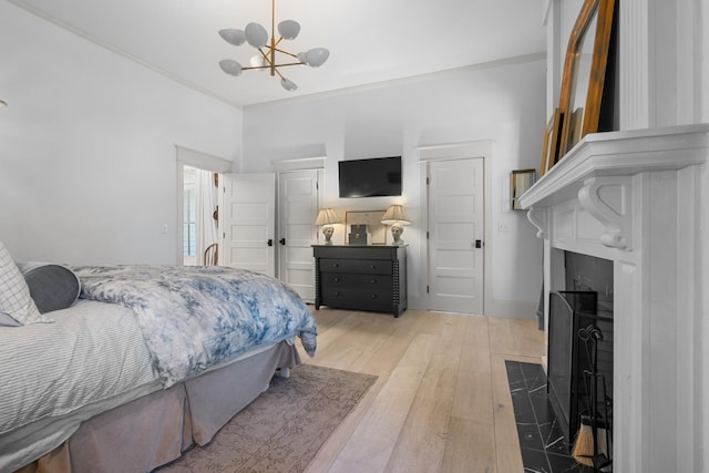 bedroom featuring a fireplace, light wood-style flooring, ornamental molding, a chandelier, and baseboards