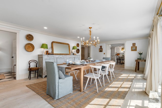 dining room featuring decorative columns, light wood finished floors, ornamental molding, a chandelier, and baseboards