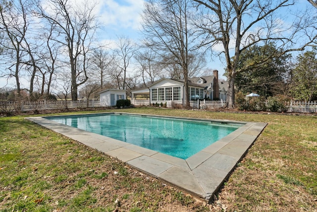 view of pool with an outbuilding, a lawn, fence, and a fenced in pool