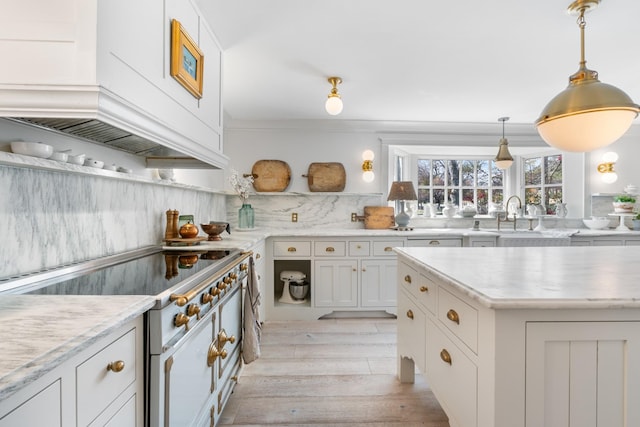 kitchen with stove, a sink, white cabinetry, light wood-type flooring, and tasteful backsplash