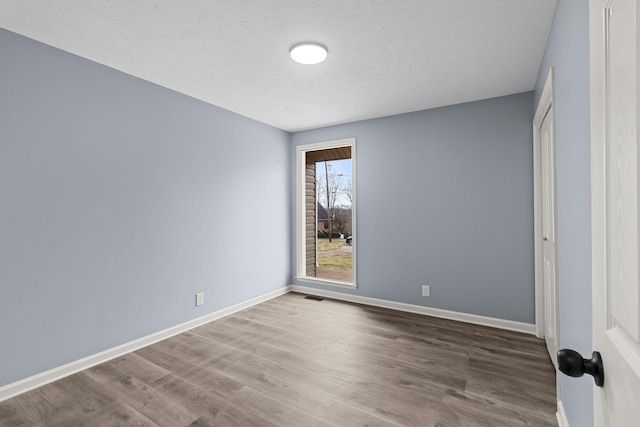 unfurnished bedroom featuring visible vents, baseboards, and wood finished floors