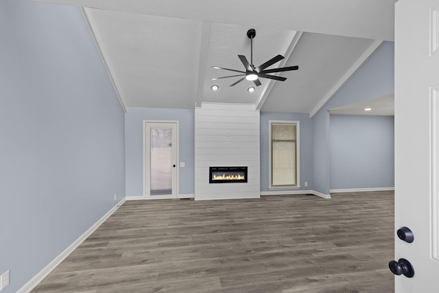 unfurnished living room with a ceiling fan, a large fireplace, vaulted ceiling, and wood finished floors