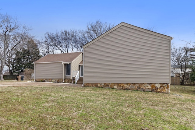 view of property exterior with entry steps and a lawn