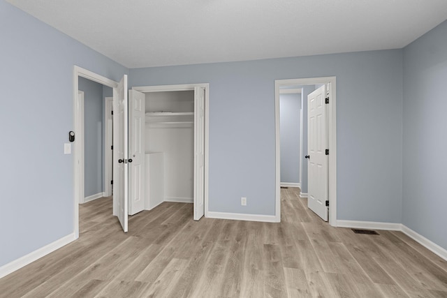 unfurnished bedroom with a closet, visible vents, light wood-style flooring, and baseboards