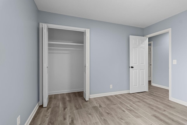 unfurnished bedroom with a closet, baseboards, and wood finished floors