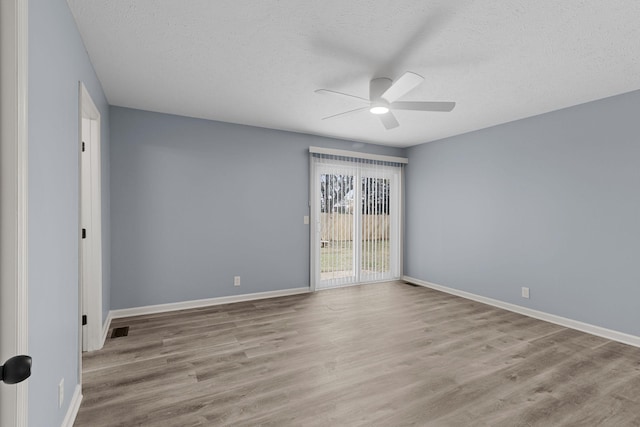 unfurnished room with a textured ceiling, wood finished floors, a ceiling fan, and baseboards