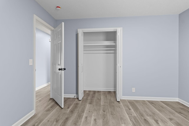 unfurnished bedroom with baseboards, a closet, and light wood-style floors