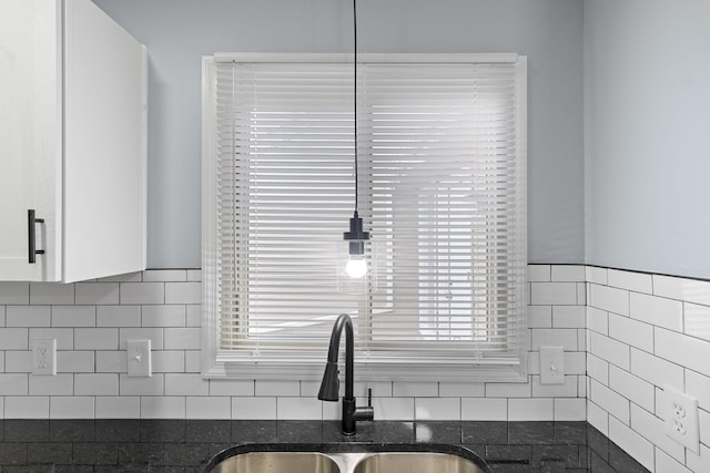 kitchen with dark stone counters, a healthy amount of sunlight, a sink, and white cabinetry