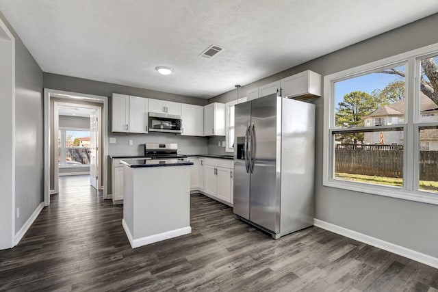 kitchen featuring visible vents, white cabinets, appliances with stainless steel finishes, a center island, and dark countertops