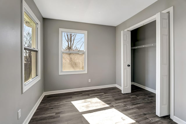 unfurnished bedroom featuring dark wood-style floors, multiple windows, and baseboards