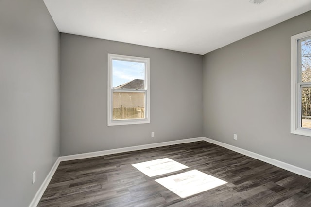 spare room featuring dark wood-style flooring and baseboards