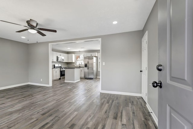 unfurnished living room featuring ceiling fan, baseboards, dark wood-style flooring, and recessed lighting