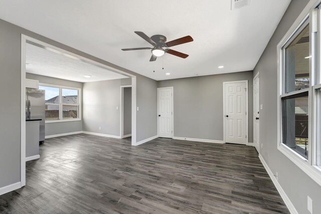 spare room with dark wood-style floors, visible vents, ceiling fan, and baseboards