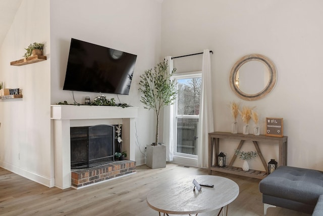 living room with a fireplace, baseboards, and wood finished floors