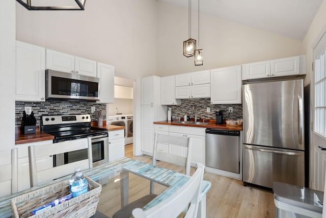 kitchen featuring washer and clothes dryer, wooden counters, light wood-style flooring, appliances with stainless steel finishes, and a sink