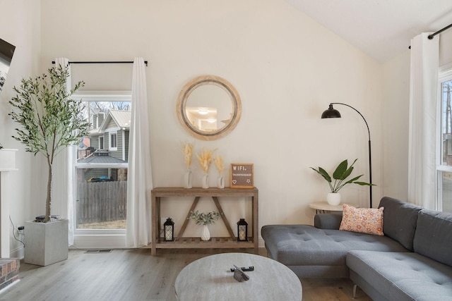 sitting room with vaulted ceiling, wood finished floors, and visible vents