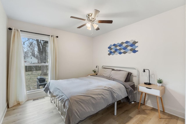 bedroom with light wood-style floors, baseboards, visible vents, and a ceiling fan