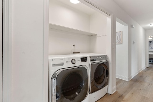 washroom featuring light wood-type flooring, laundry area, baseboards, and washer and dryer