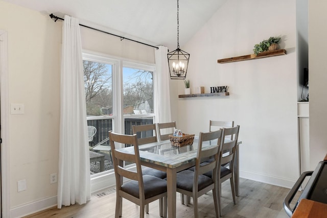 dining room with lofted ceiling, baseboards, visible vents, and light wood finished floors