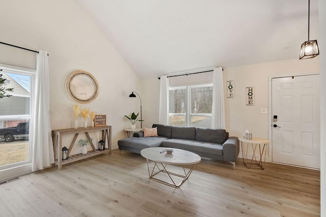 living area featuring a wealth of natural light, visible vents, and wood finished floors