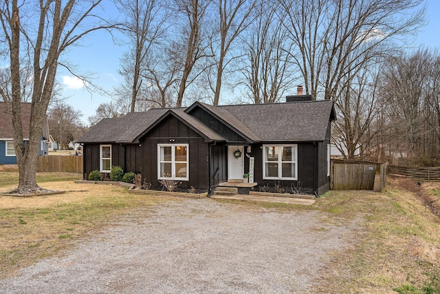 view of front of house featuring board and batten siding, fence, driveway, and a shingled roof