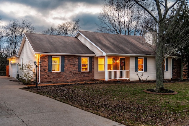 single story home featuring driveway, a chimney, covered porch, a front lawn, and brick siding