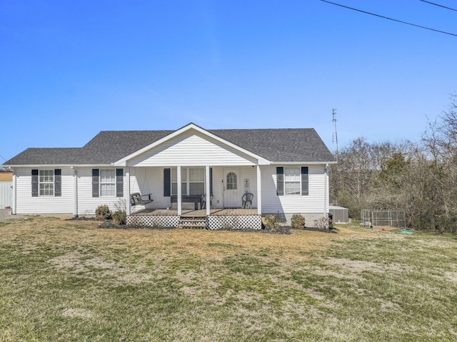 view of front facade with a porch, a front yard, a shingled roof, and central AC unit