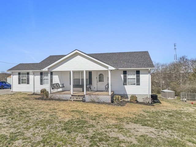 bungalow featuring covered porch, a shingled roof, an outbuilding, and a front yard