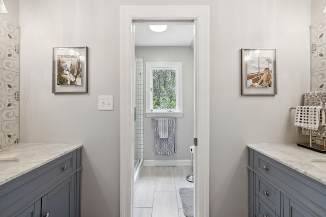 full bath featuring two vanities and baseboards