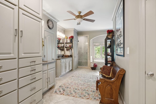 spacious closet featuring arched walkways, light tile patterned flooring, and ceiling fan