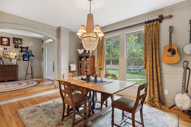 dining room with arched walkways, wood finished floors, and crown molding