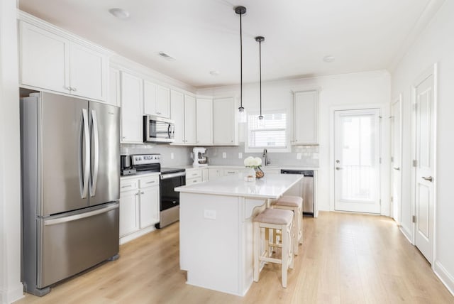 kitchen featuring light wood-style floors, a kitchen bar, appliances with stainless steel finishes, and white cabinets