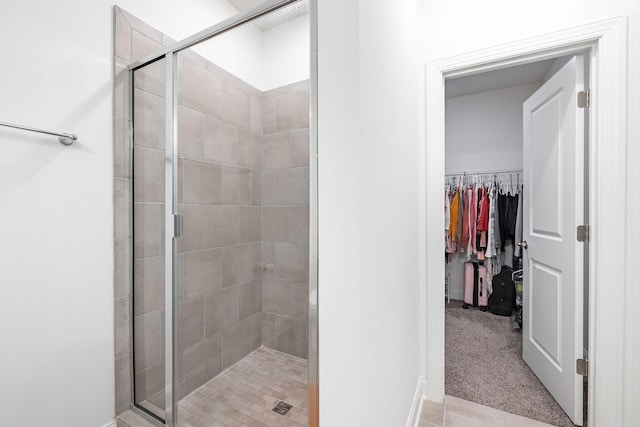 bathroom featuring a stall shower, a walk in closet, and tile patterned floors