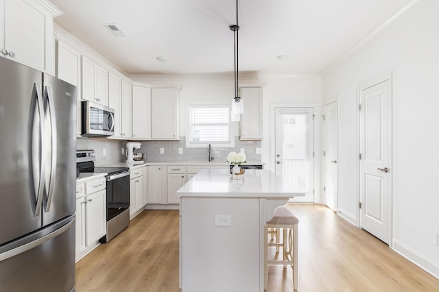 kitchen with stainless steel appliances, a breakfast bar, light wood-style flooring, and backsplash