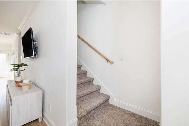 staircase featuring ornamental molding, carpet flooring, visible vents, and baseboards