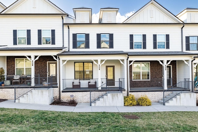 multi unit property featuring covered porch, stairway, board and batten siding, and brick siding