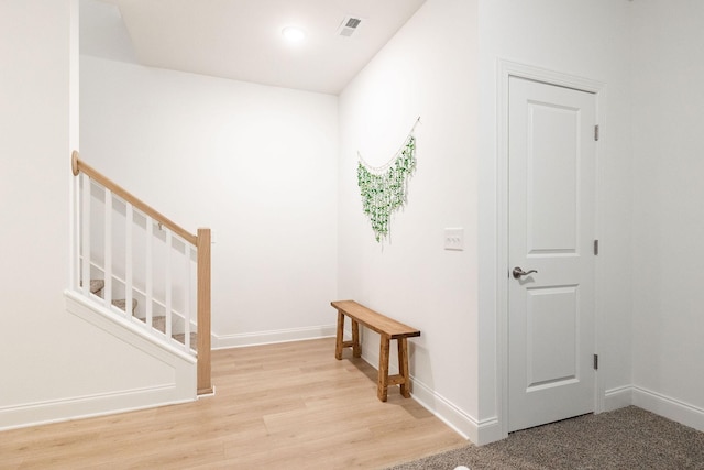 hall with visible vents, light wood finished floors, baseboards, and stairs