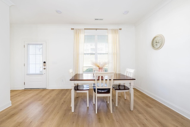 dining space with crown molding, light wood finished floors, visible vents, and baseboards