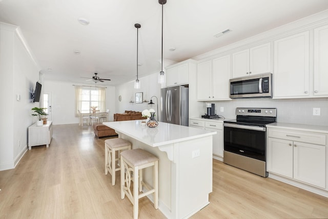 kitchen with visible vents, decorative backsplash, a kitchen island, open floor plan, and stainless steel appliances