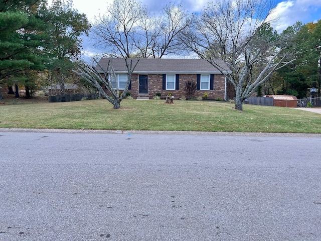 view of front of property featuring a front lawn, fence, and brick siding