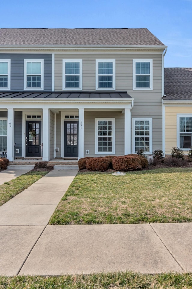 view of front facade with a front yard, roof with shingles, a standing seam roof, a porch, and metal roof