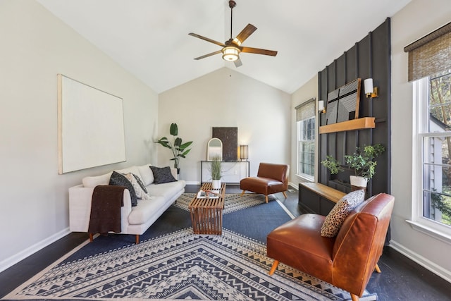 living area featuring a ceiling fan, a healthy amount of sunlight, vaulted ceiling, and baseboards