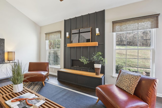 living area featuring lofted ceiling, a fireplace, wood finished floors, and baseboards